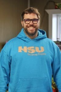 Sales Manager, Justin Osswald, standing in our retail store with a light blue Hsu branded sweatshirt